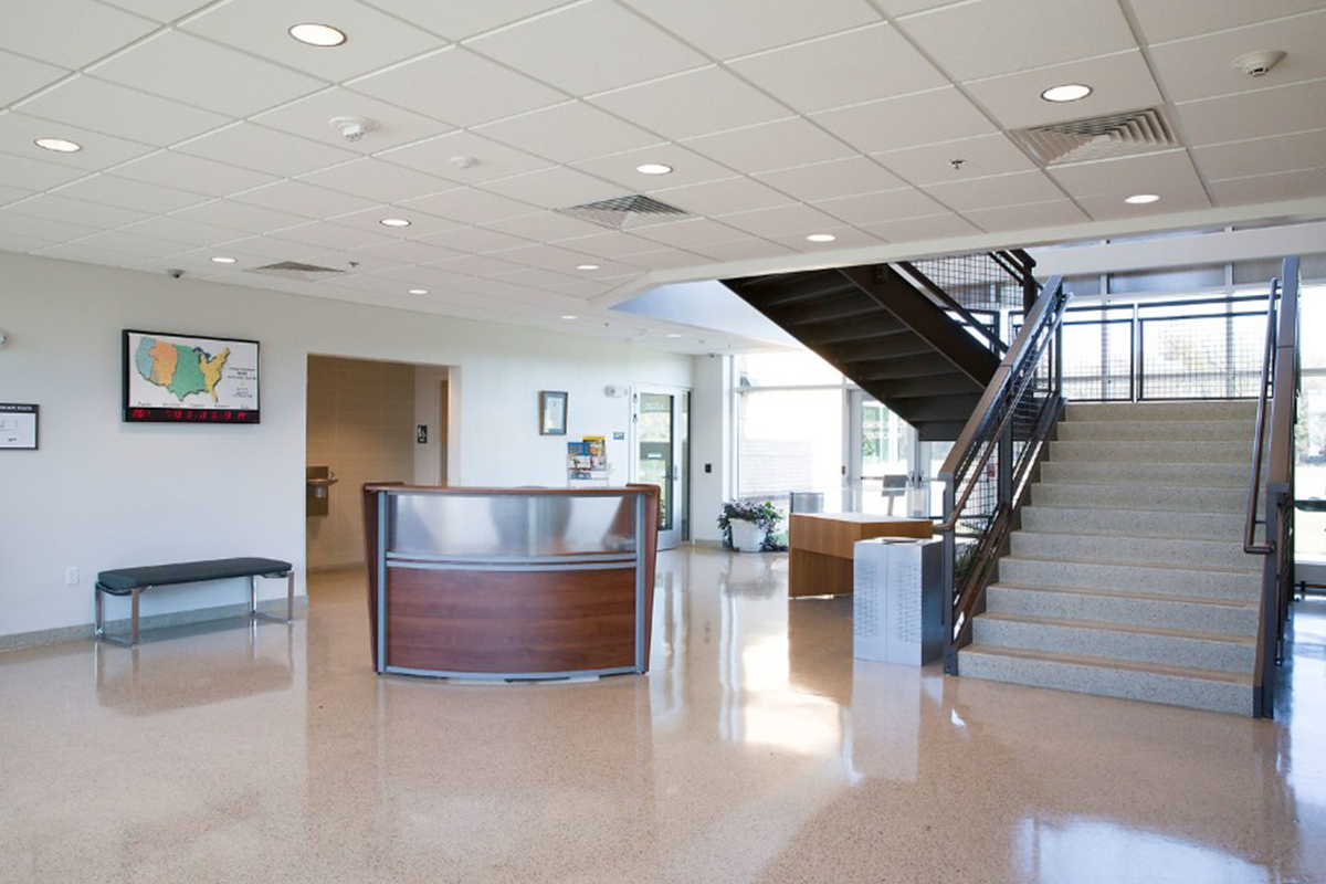 A lobby with a large staircase and a reception desk.