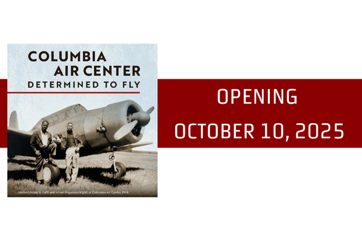 Text reading: Columbia Air Center - Determined To Fly - Opening October 10, 2025; A black and white image of two men standing in front of an old propeller plane.