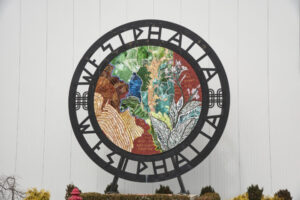 Circular artwork that reads WESTPHALIA around the top and bottom. Inside the circle is a colorful artwork or mosaic with leaves and flowers.