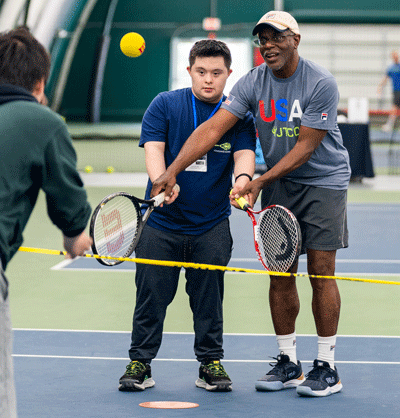 person with disability getting assistance playing tennis