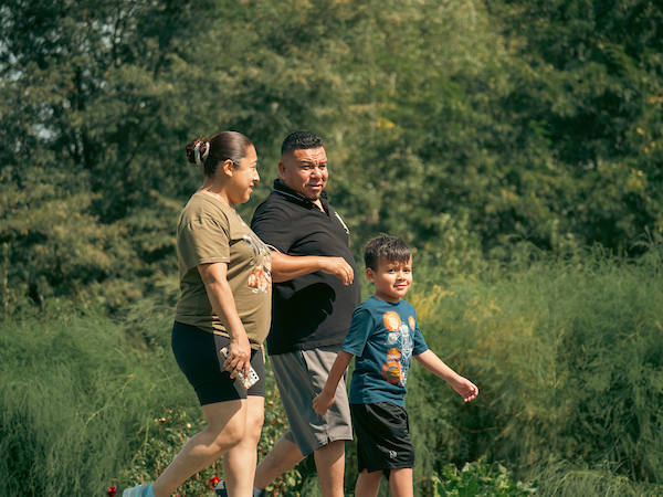 A family of three walking in a park.