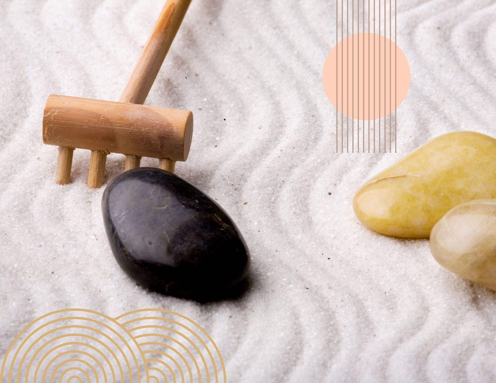 A small wooden rake and smooth rocks resting on raked white sand in a tabletop Zen garden.